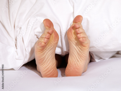 Happy feet under a white blanket