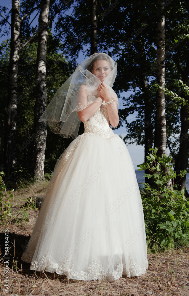 The bride in a wedding dress in park in the summer.
