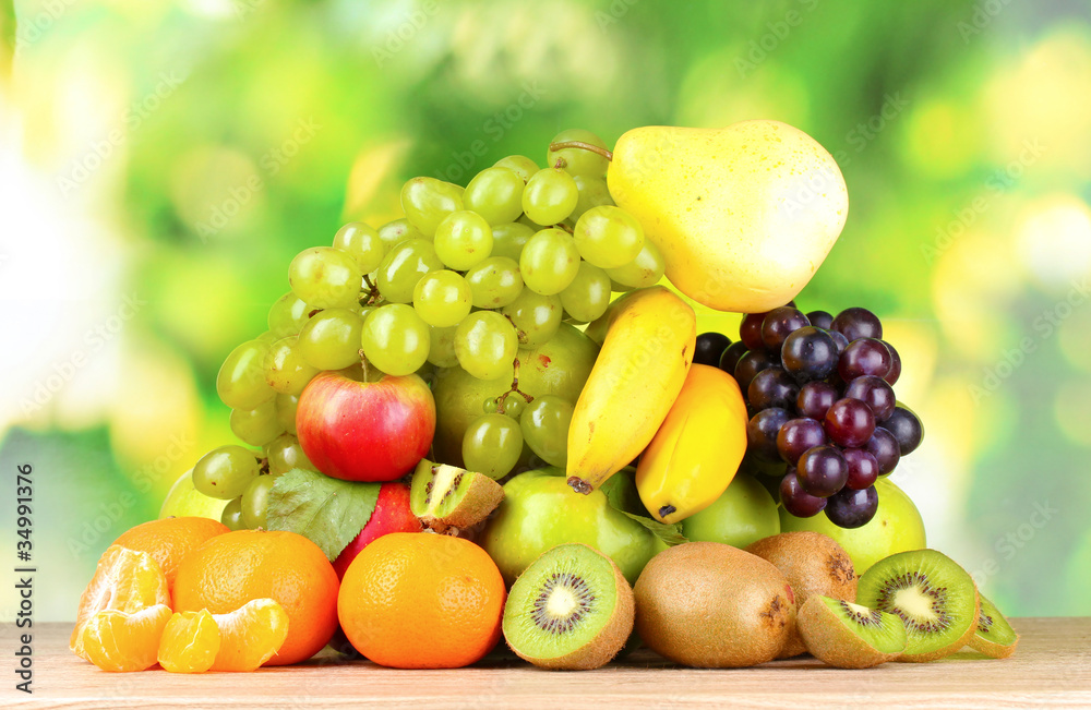 Ripe juicy fruits on wooden table on green background Ripe juicy fruits on wooden table on green background