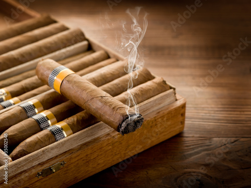 Canvas Print smoking cuban cigar over box  on wood background