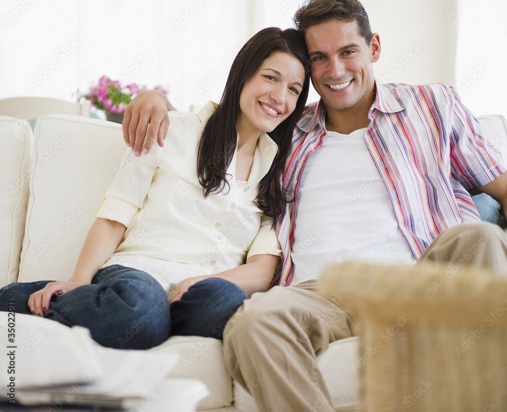 Smiling couple sitting on sofa together Smiling couple sitting on sofa together