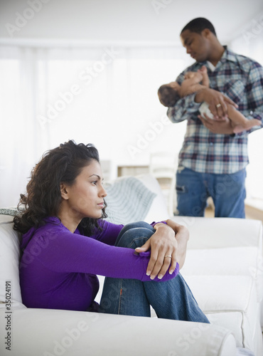 Sad mother with father holding baby in background photo