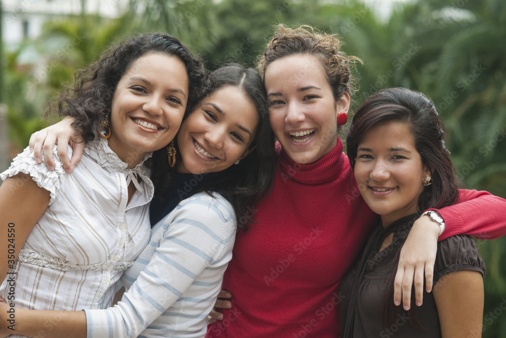 Smiling Hispanic friends hugging Smiling Hispanic friends hugging