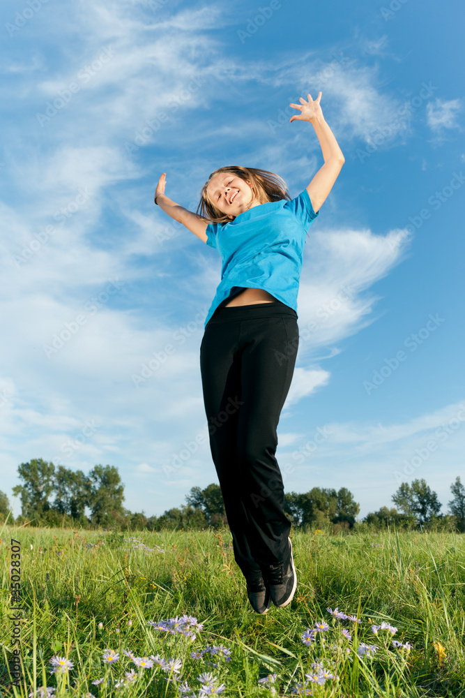 Happy girl jumps against a green grass and the blue sky Happy girl jumps against a green grass and the blue sky