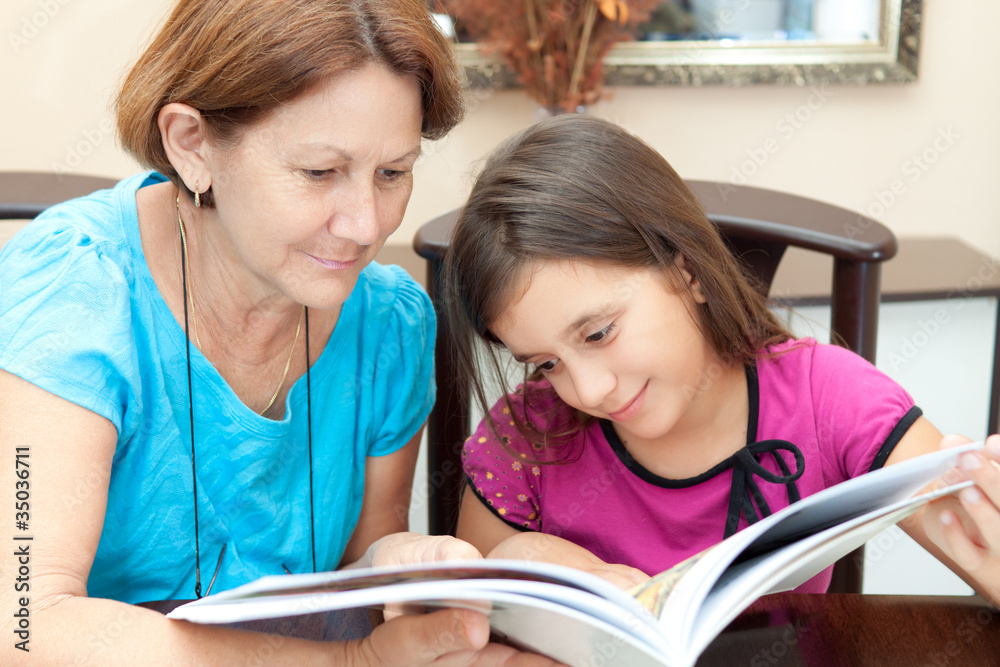 Grandmother and granddaughter reading a book at home Grandmother and granddaughter reading a book at home