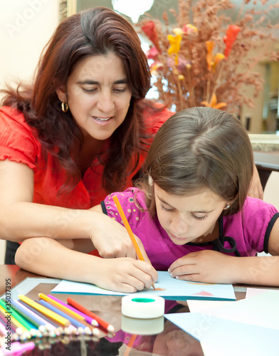 Latin mother helping her daughter with school homework