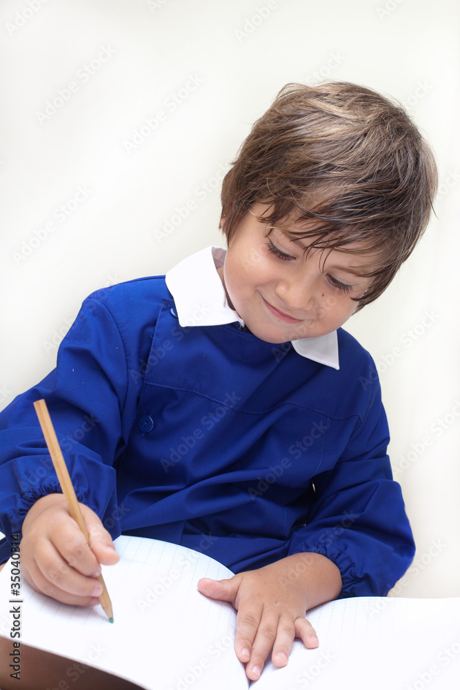 bambino con grembiule scrive nel quaderno bambino con grembiule scrive nel quaderno