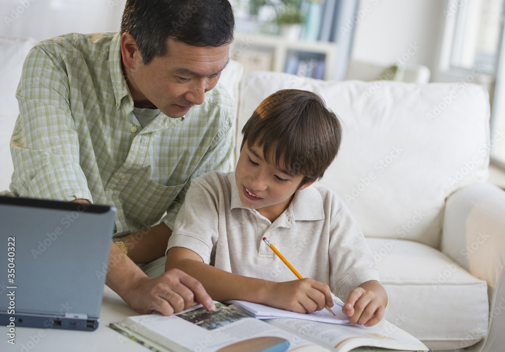 Father helping son with homework in living room Father helping son with homework in living room