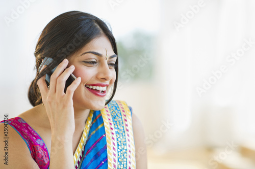 Mixed race woman in traditional Indian clothing talking on cell phone