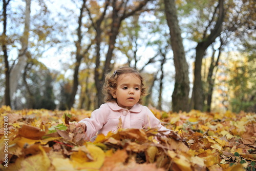 Girl covered with leaves in the park