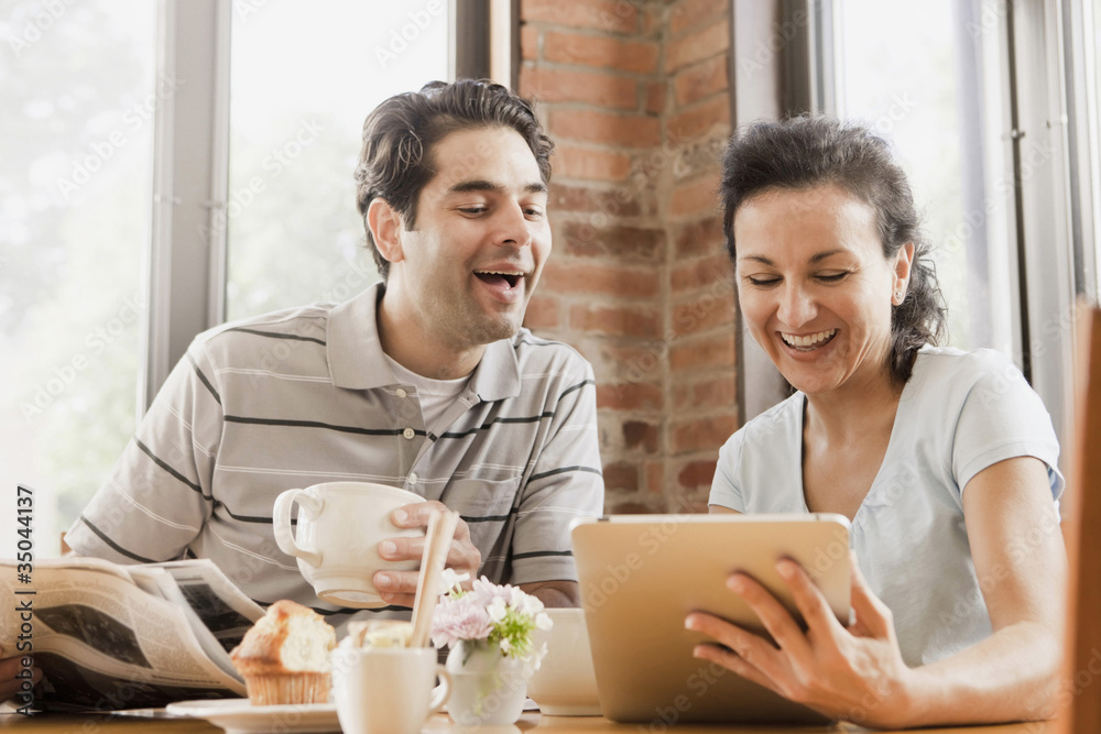 Hispanic couple using digital tablet in cafe Hispanic couple using digital tablet in cafe
