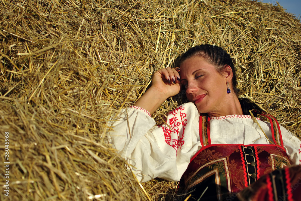 girl in traditional Russian costume resting on a haystack girl in traditional Russian costume resting on a haystack