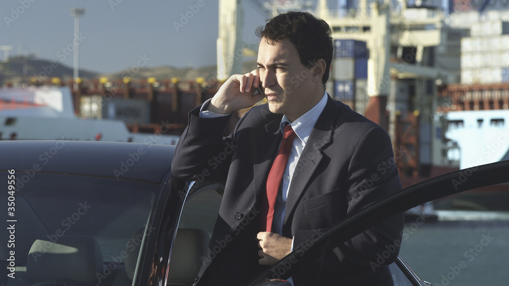 Hispanic businessman talking on cell phone on dock Hispanic businessman talking on cell phone on dock