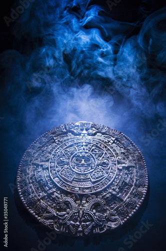 Aztec calendar stone carving surrounded by smoke photo