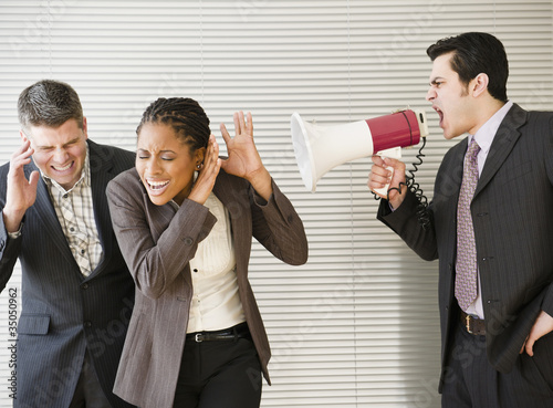 Businessman shouting through bullhorn at co-workers