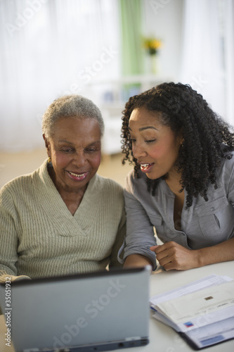 Daughter using laptop with mother photo