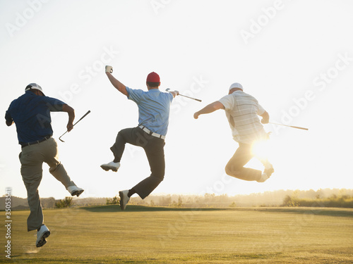 Excited golfers jumping in mid-air on golf course