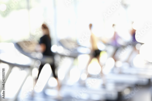 Defocused view of people on treadmills in health club photo