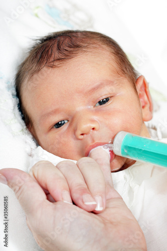 little boy drinking milk from the mother of the syringe