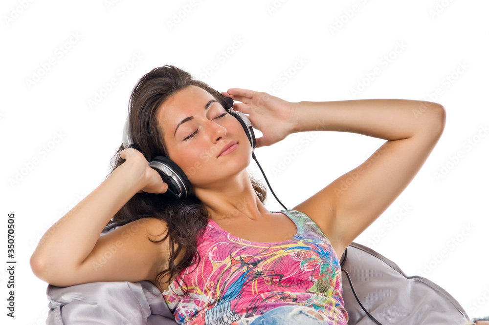 Naklejka premium Young beautiful dark haired woman listening music in headphones