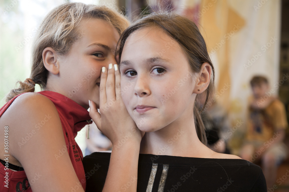 Young girl whispers something in another one's ear Young girl whispers something in another one's ear