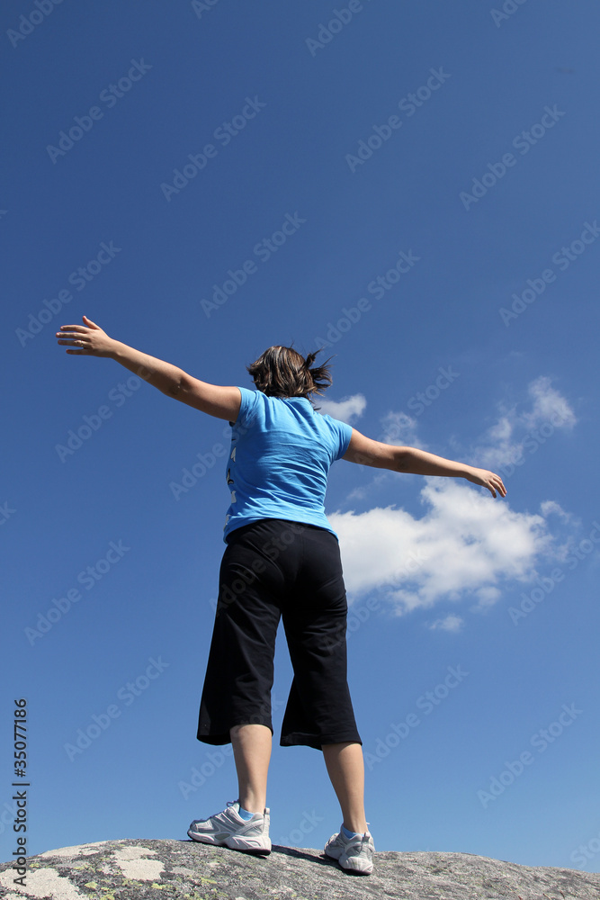 young woman with arms wide open against blue sky young woman with arms wide open against blue sky