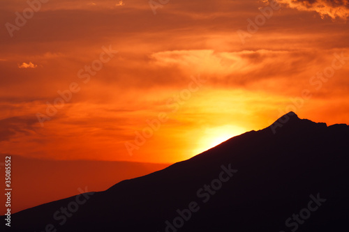 clouded orange sky with mountain silhouette