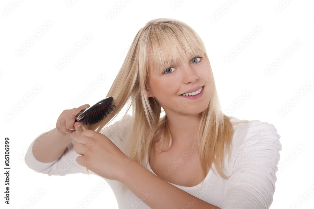 junge blonde frau kaemmt sich die haare