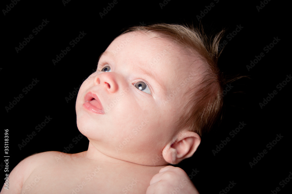 Baby boy on black background looks up in curiousity Baby boy on black background looks up in curiousity