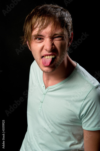 Handsome young man making funny face sticking out tongue © Alex Tihonov