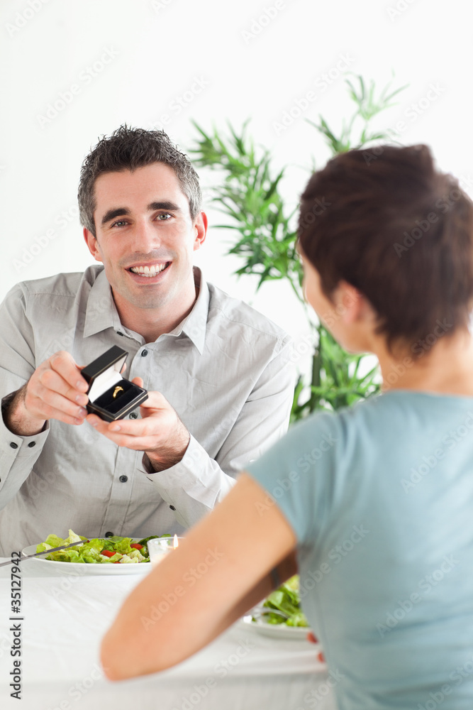 Smiling Man proposing to his surprised girlfriend during dinner Smiling Man proposing to his surprised girlfriend during dinner