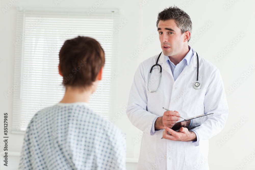 Serious Doctor talking to a woman in hospital gown Serious Doctor talking to a woman in hospital gown