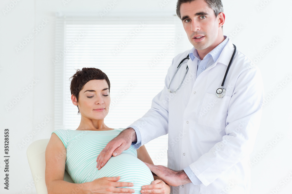 Male Doctor examining a pregnant woman's tummy Male Doctor examining a pregnant woman's tummy