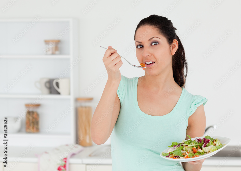 Lovely young woman with salad in kitchen