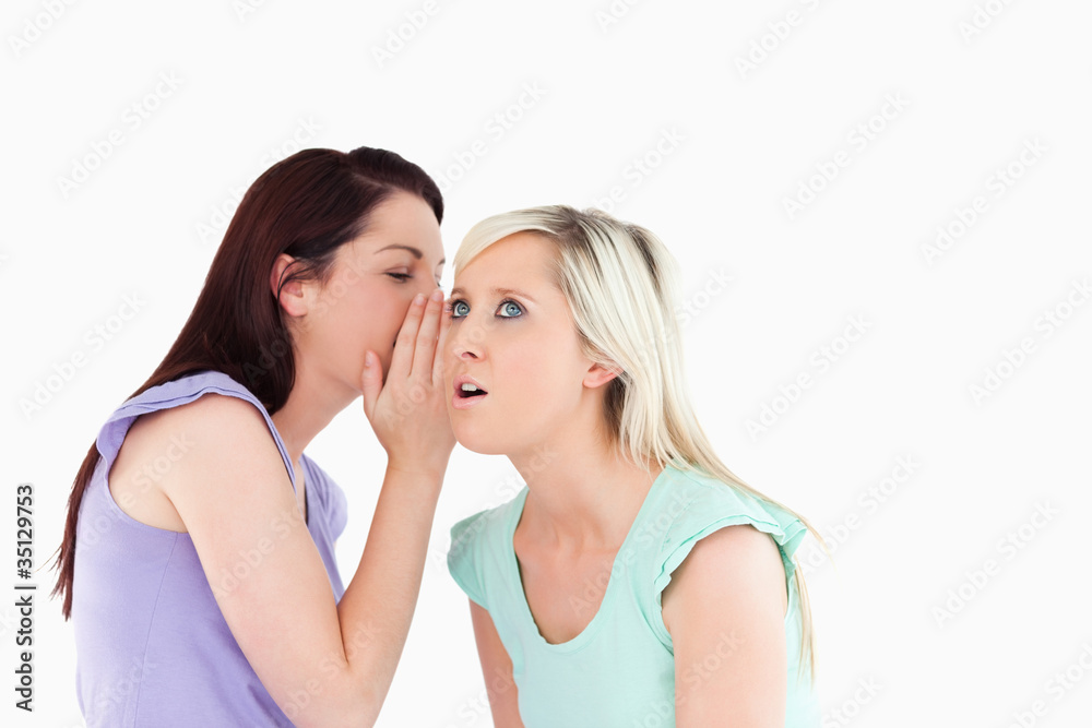 Portrait of a cute woman telling her friend a secret Portrait of a cute woman telling her friend a secret
