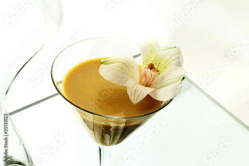 A wineglass with a liqueur and a flower