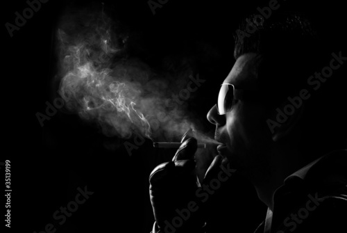 Man blows smoke on a dark