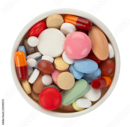 Colored pills in white bowl - top view