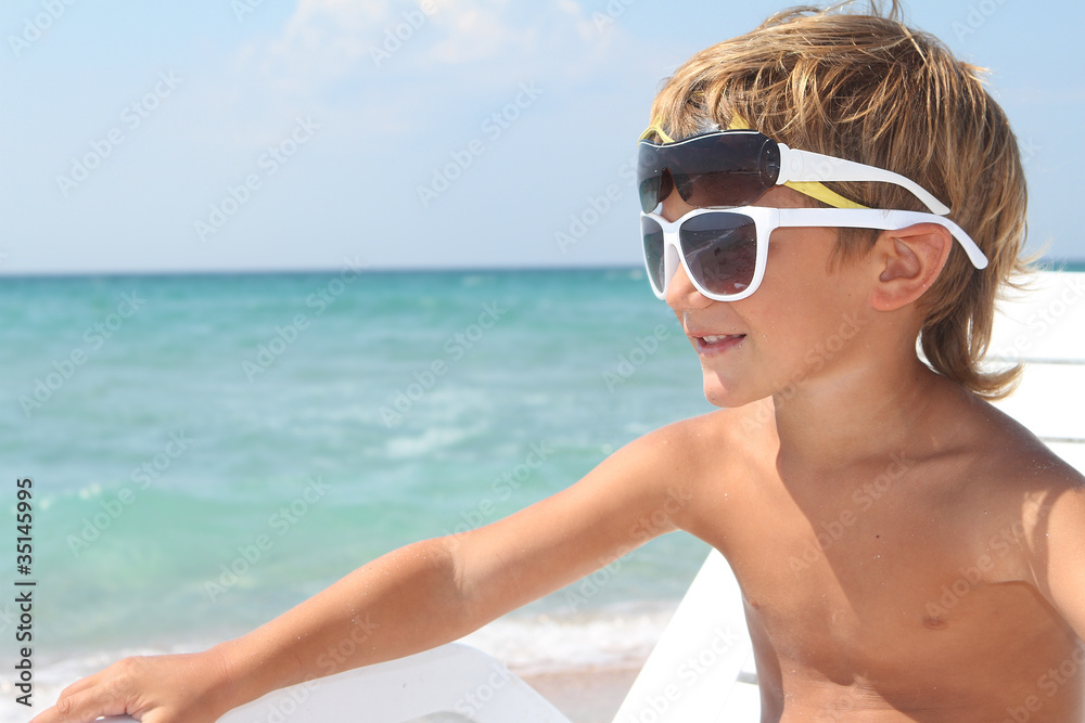 Fototapeta premium young boy in sun glasses on sea background