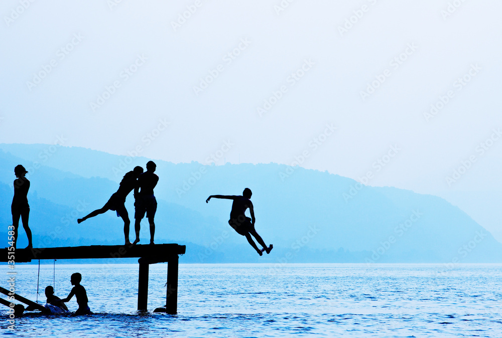 Silhouettes of kids who jump off dock on the lake Stock Photo Adobe Stock