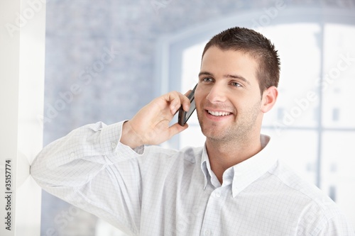 Young man talking on mobile phone smiling