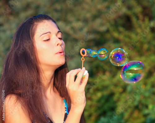 Pretty woman inflating soap-bubbles