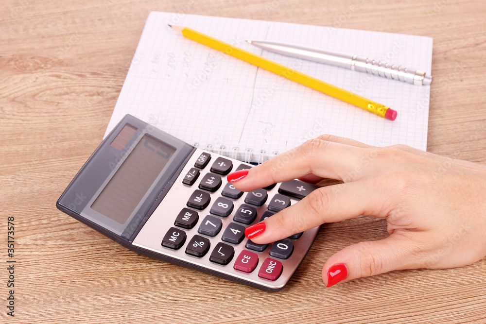 hand, notepad and calculator on wooden background hand, notepad and calculator on wooden background