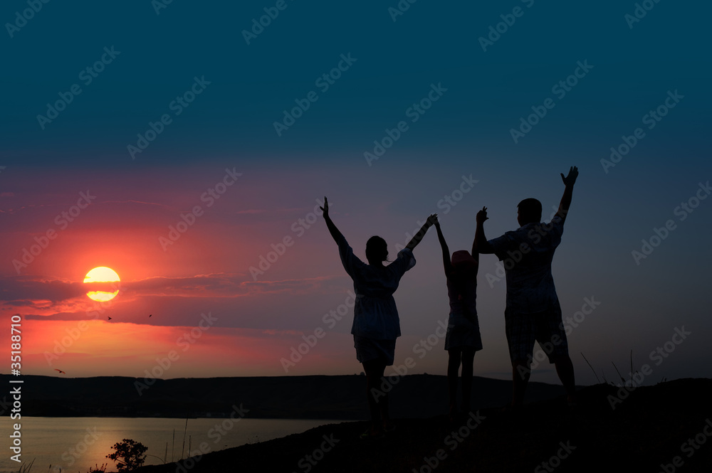 Fototapeta premium The family from three persons welcomes the sunset sun