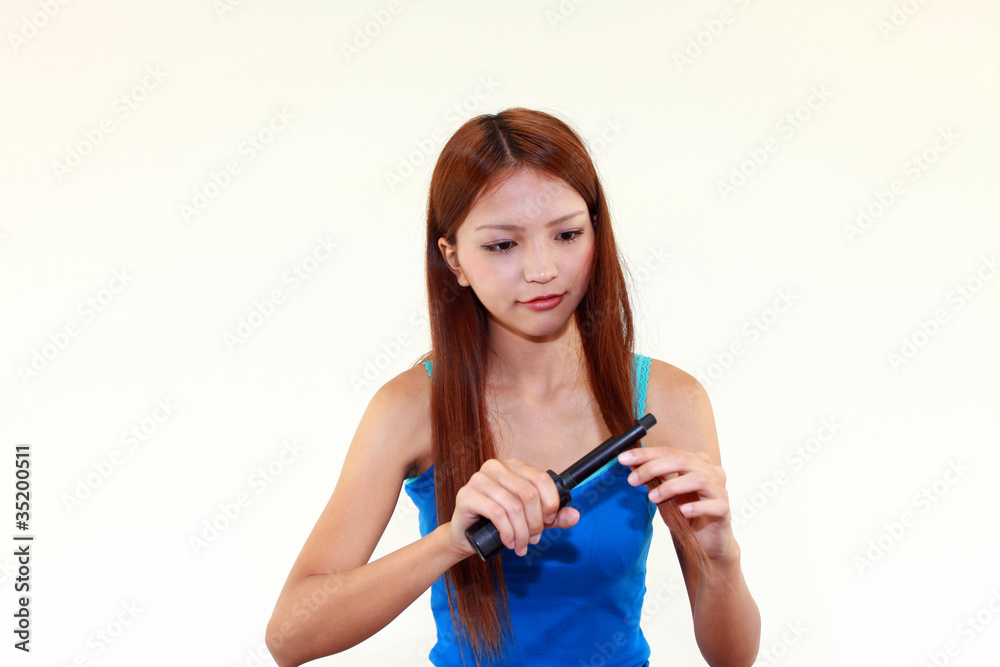 毛先をコテでカールする女性 毛先をコテでカールする女性