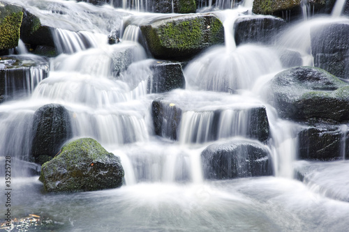 Beautiful waterfall cascades over rocks in lush forest landscape