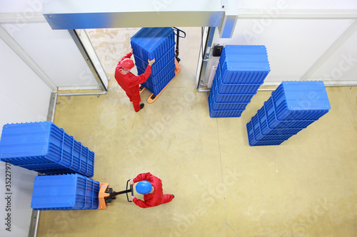 two workers loading plastic boxes in small warehouse photo