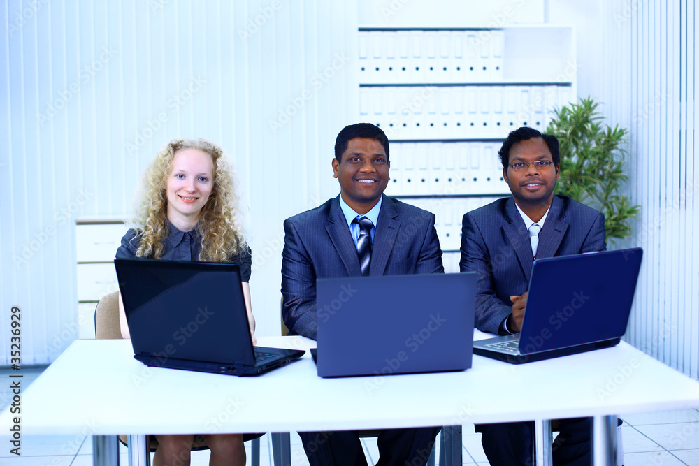 Interracial business team working at laptop in a Interracial business team working at laptop in a