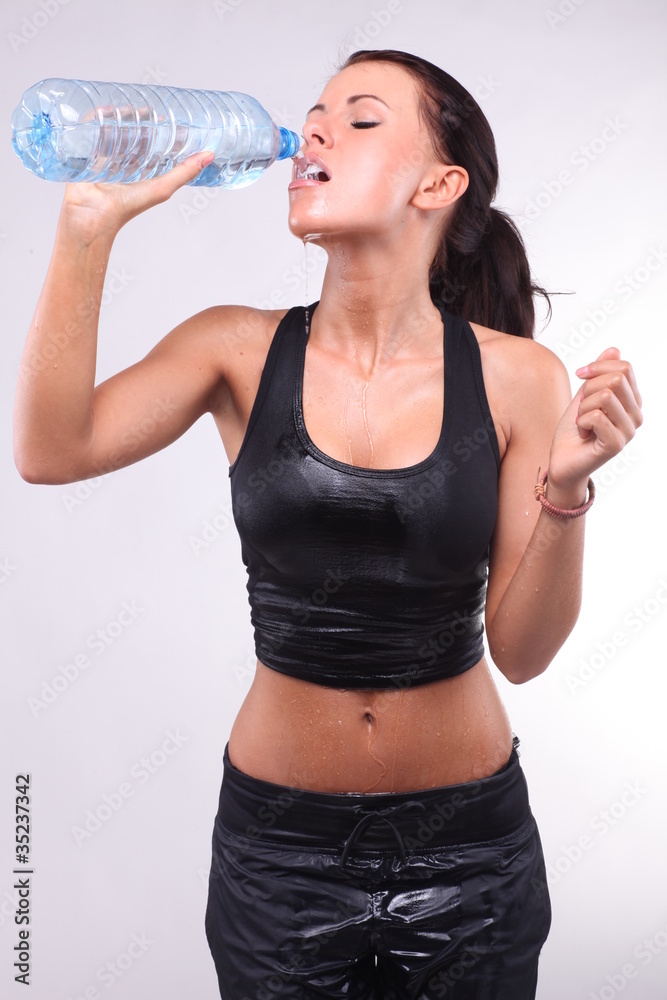 Atractive female drinking water after doing sports. Atractive female drinking water after doing sports.