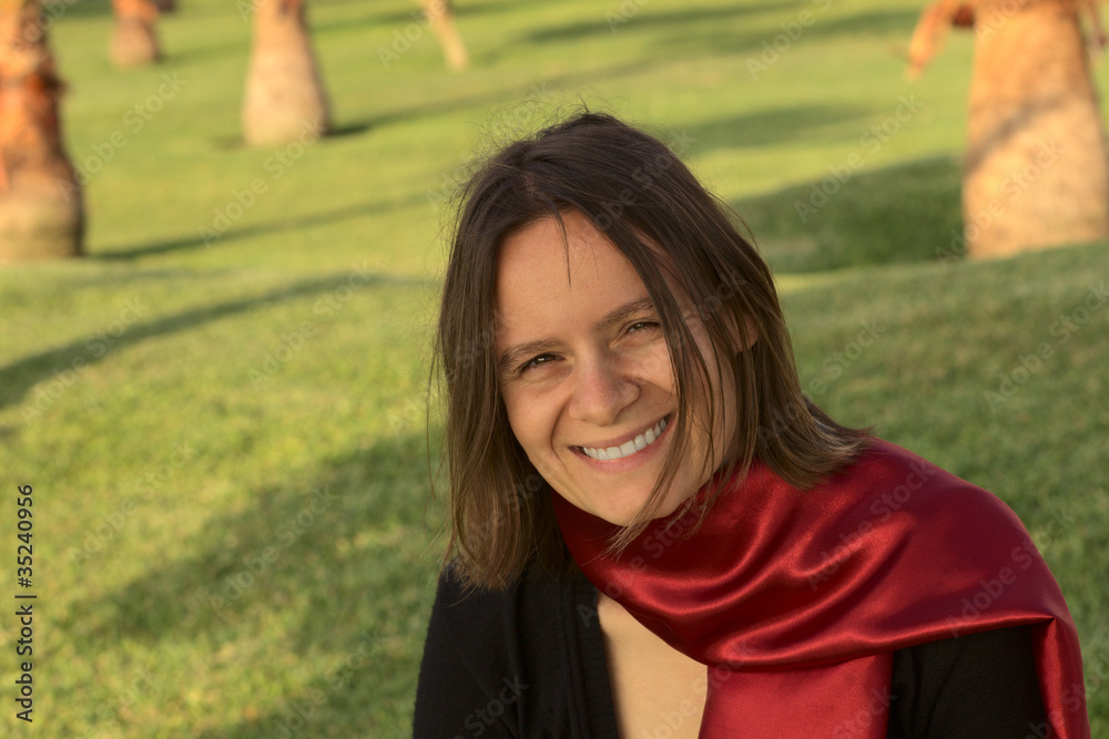 Portrait of a smiling young woman with a red scarf in a park Portrait of a smiling young woman with a red scarf in a park